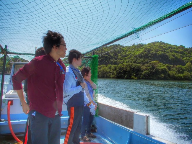 沖島の漁師さんの船に乗り、港の清掃へ行く学生ボランティア