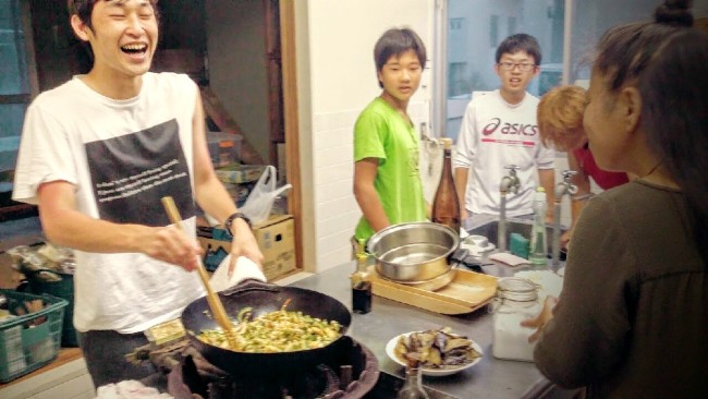 ゴーヤチャンプルに素麺を混ぜたものとナスの味噌炒めを作る諏訪之瀬島の学生ボランティア