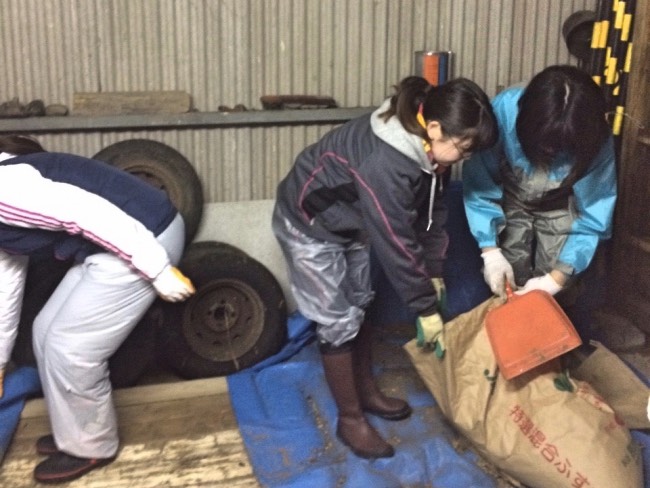 片泊の牛舎の中の倉庫の掃除をする学生ボランティア
